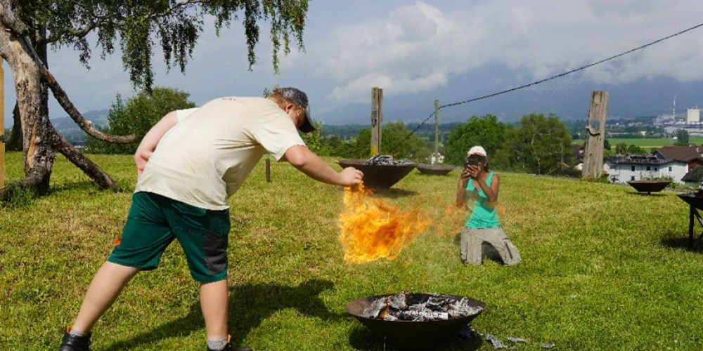 Eine Person hält seine Hand in die Flammen einer Feuerschale. 