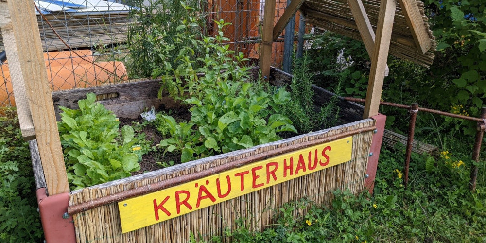 Foto von einem Beet, das mit Kräutern bepflanzt ist. Gross beschriftet mit Kräuterhaus.